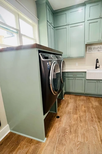Laundry room with green cabinetry.