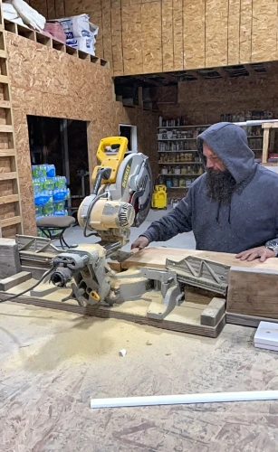 Carpenter working with mitre saw in workshop.