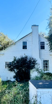Cozy white cottage with brick chimney and autumn foliage